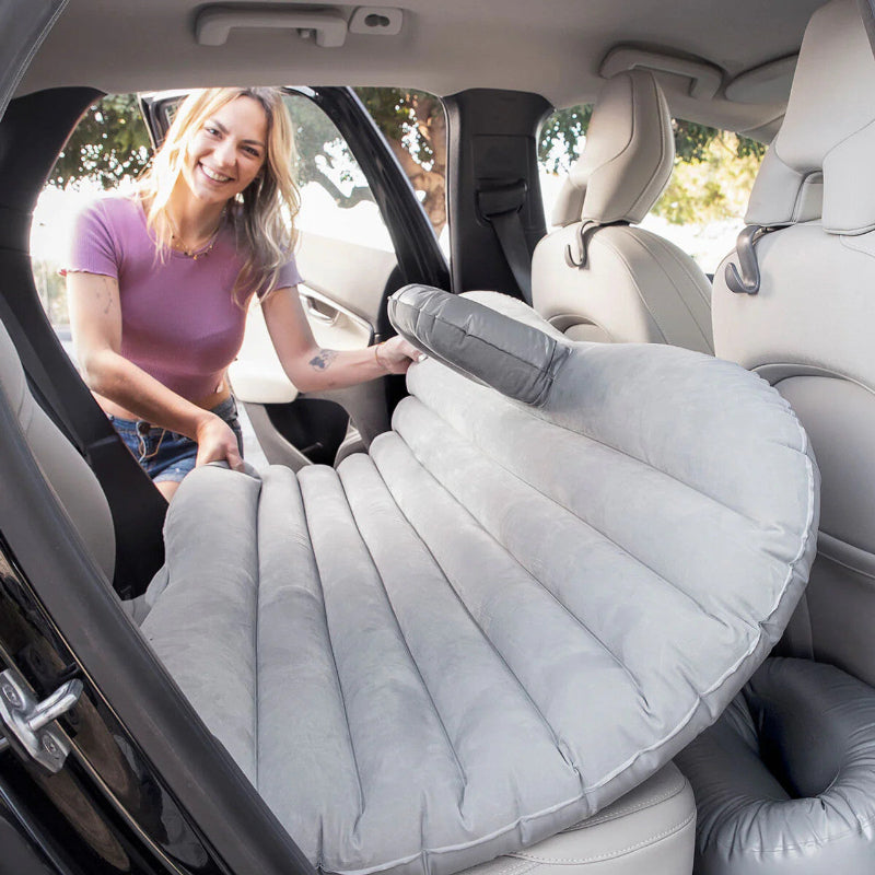 Woman setting up an inflatable car seat cover in a vehicle.